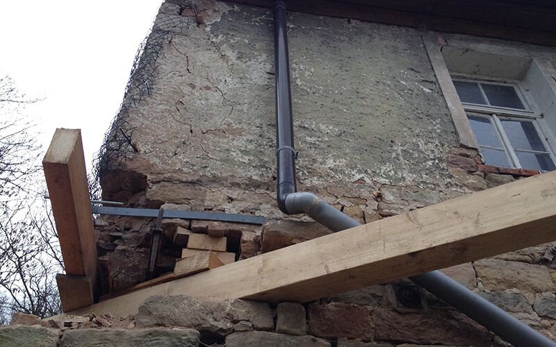 Blick auf die Sicherung des Wirtschaftsgebäudes durch einen Holzbalken